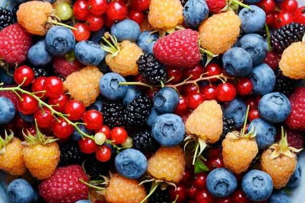 Frutas rojas y bayas frescas en una superficie clara